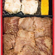 「米沢牛炭火焼 特上カルビ弁」 職人が手作業で丁寧にさばいた米沢牛の特上カルビ肉を炭火で焼き上げ。香ばしくジューシーな焼き肉のほか、うまみがたっぷり詰まった焼売が2個も付きボリューム満点