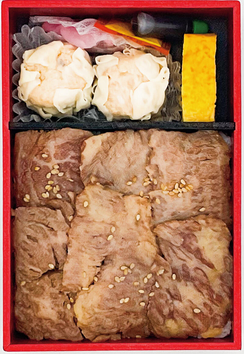 「米沢牛炭火焼 特上カルビ弁」 職人が手作業で丁寧にさばいた米沢牛の特上カルビ肉を炭火で焼き上げ。香ばしくジューシーな焼き肉のほか、うまみがたっぷり詰まった焼売が2個も付きボリューム満点